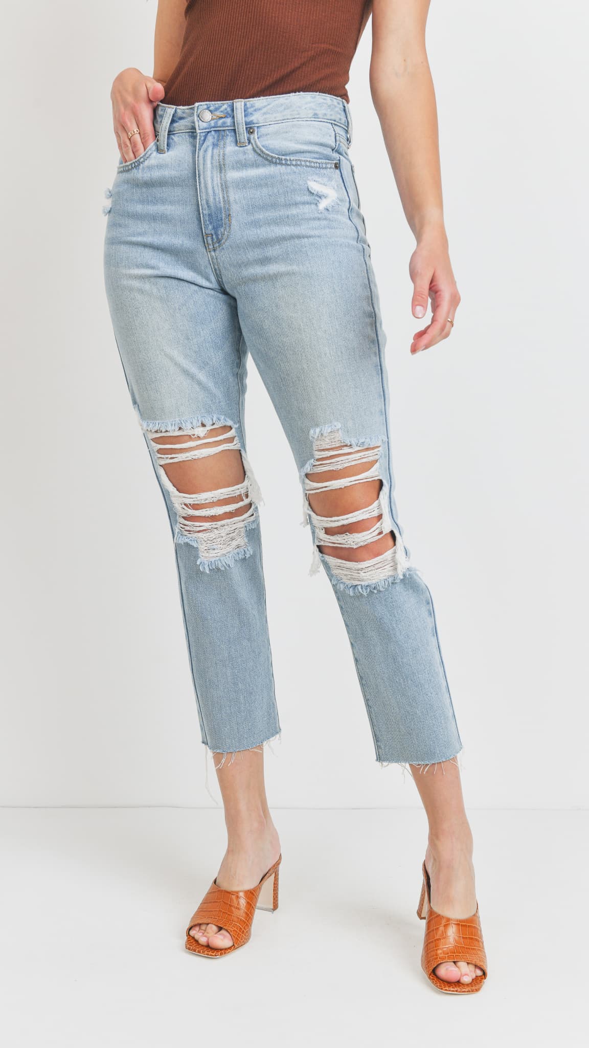 Close up of light-wash distressed straight-leg jeans, a brown tank top, and heeled mules