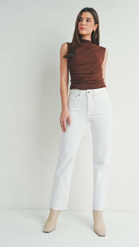 Woman in white straight-leg jeans, a brown sleeveless top, and beige boots
