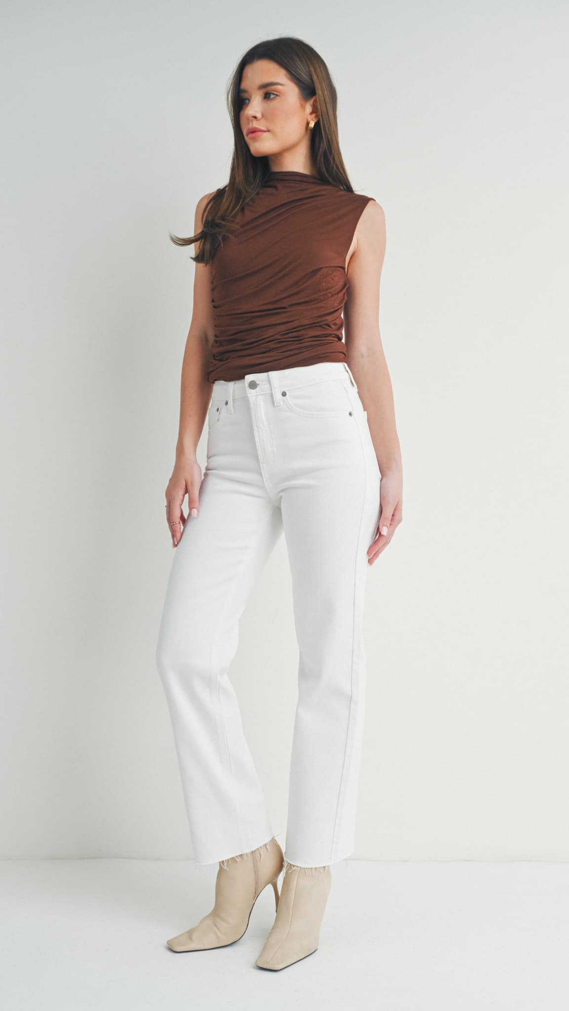 Woman in white straight-leg jeans, a brown sleeveless top, and beige heeled boots
