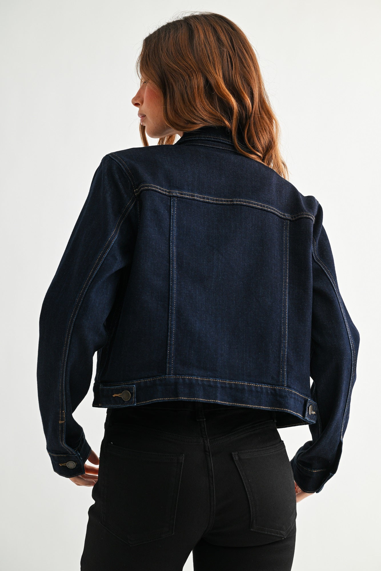 Person wearing a dark blue denim jacket on a white background