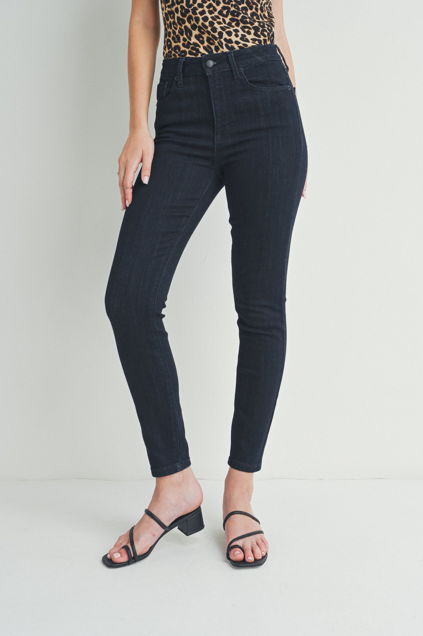 Person wearing black jeans and a leopard print top on a plain background