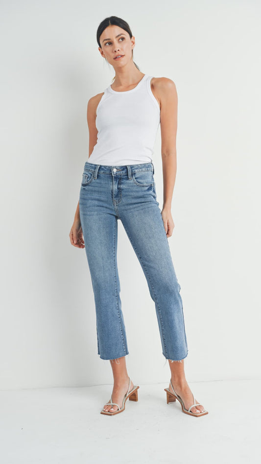 Woman wearing medium-wash cropped flare jeans, a white tank top, and heeled sandals.