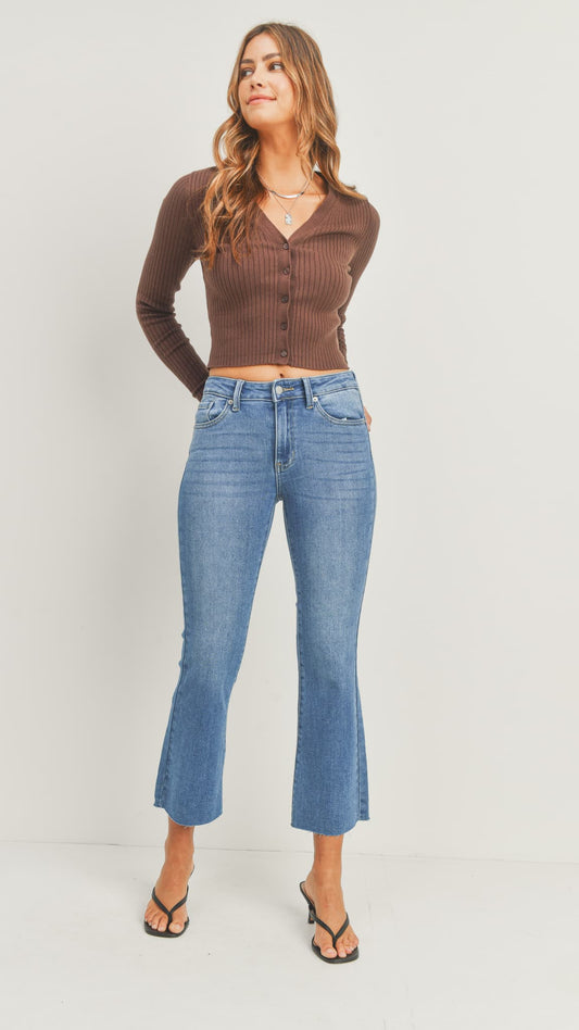 Woman in medium-wash flared jeans, a brown long-sleeve top, and heeled sandals