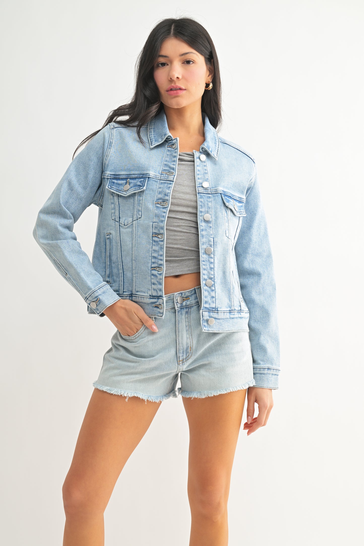 Woman wearing a light blue denim jacket and shorts on a white background