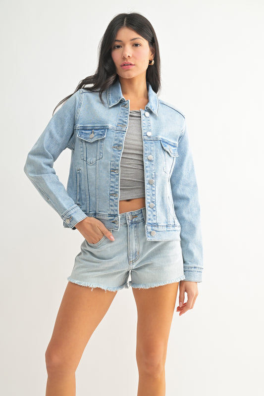 Woman wearing a light blue denim jacket and shorts on a white background