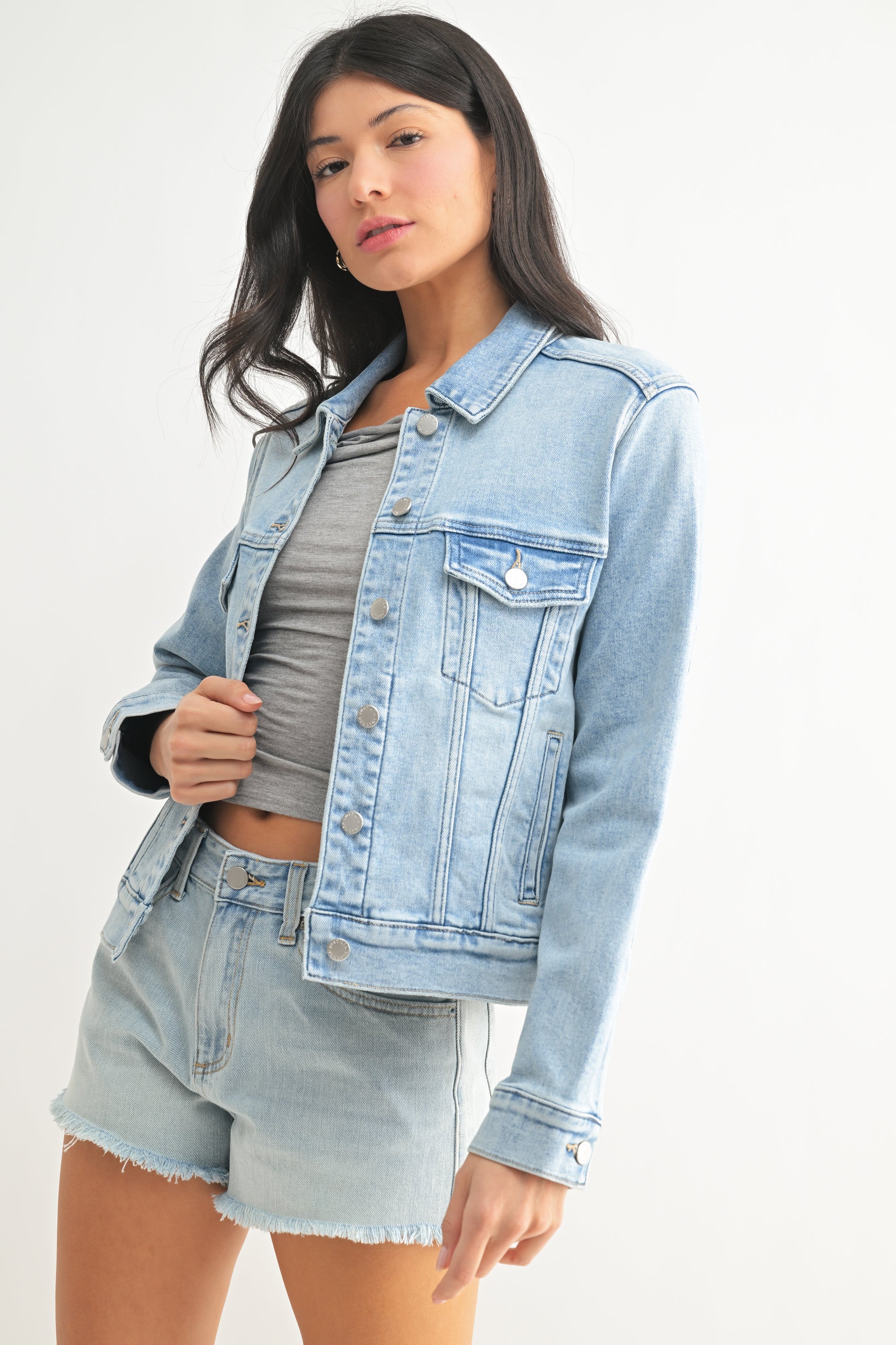 Woman wearing a light blue denim jacket and shorts on a white background