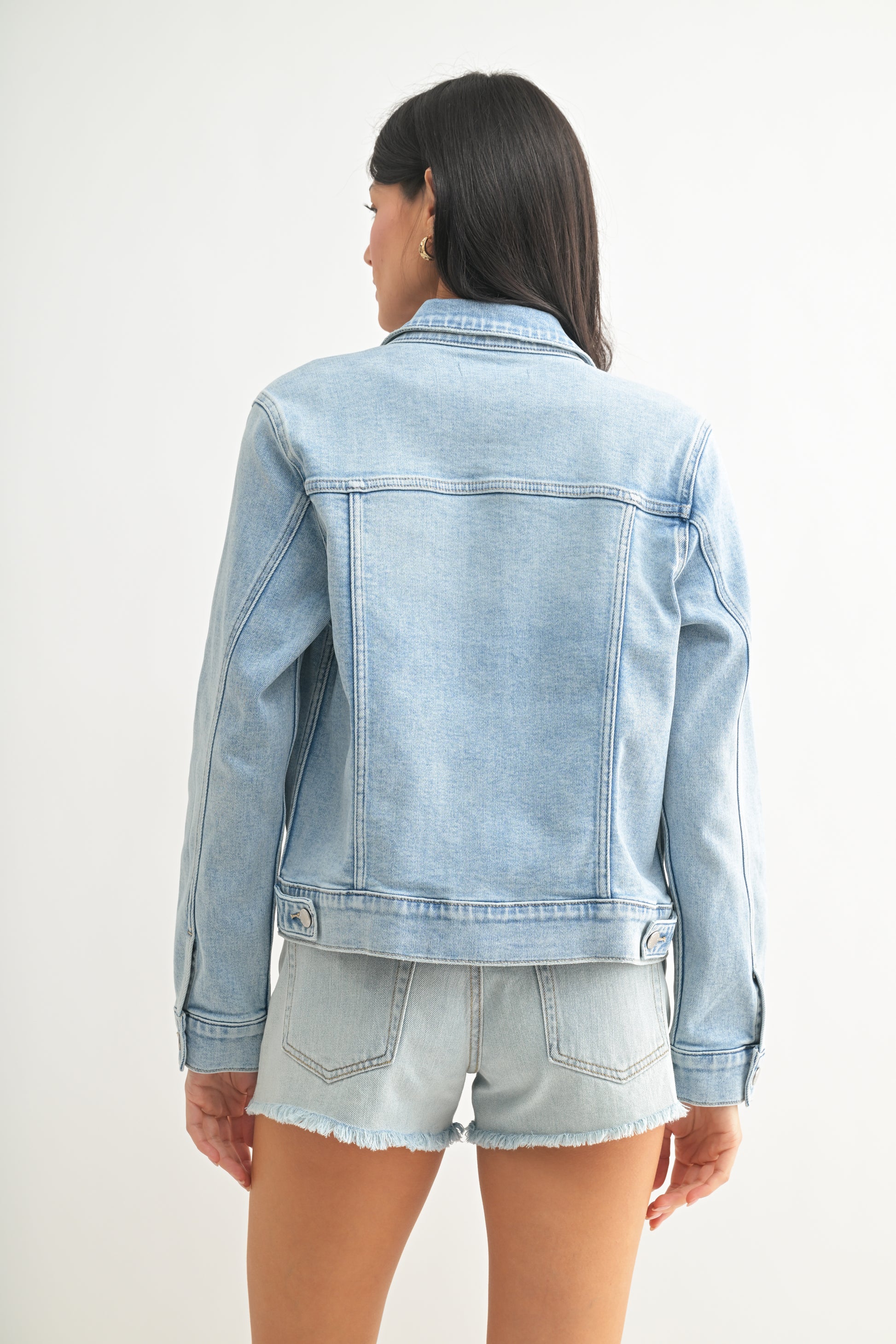 Person wearing a light blue denim jacket and shorts on a white background
