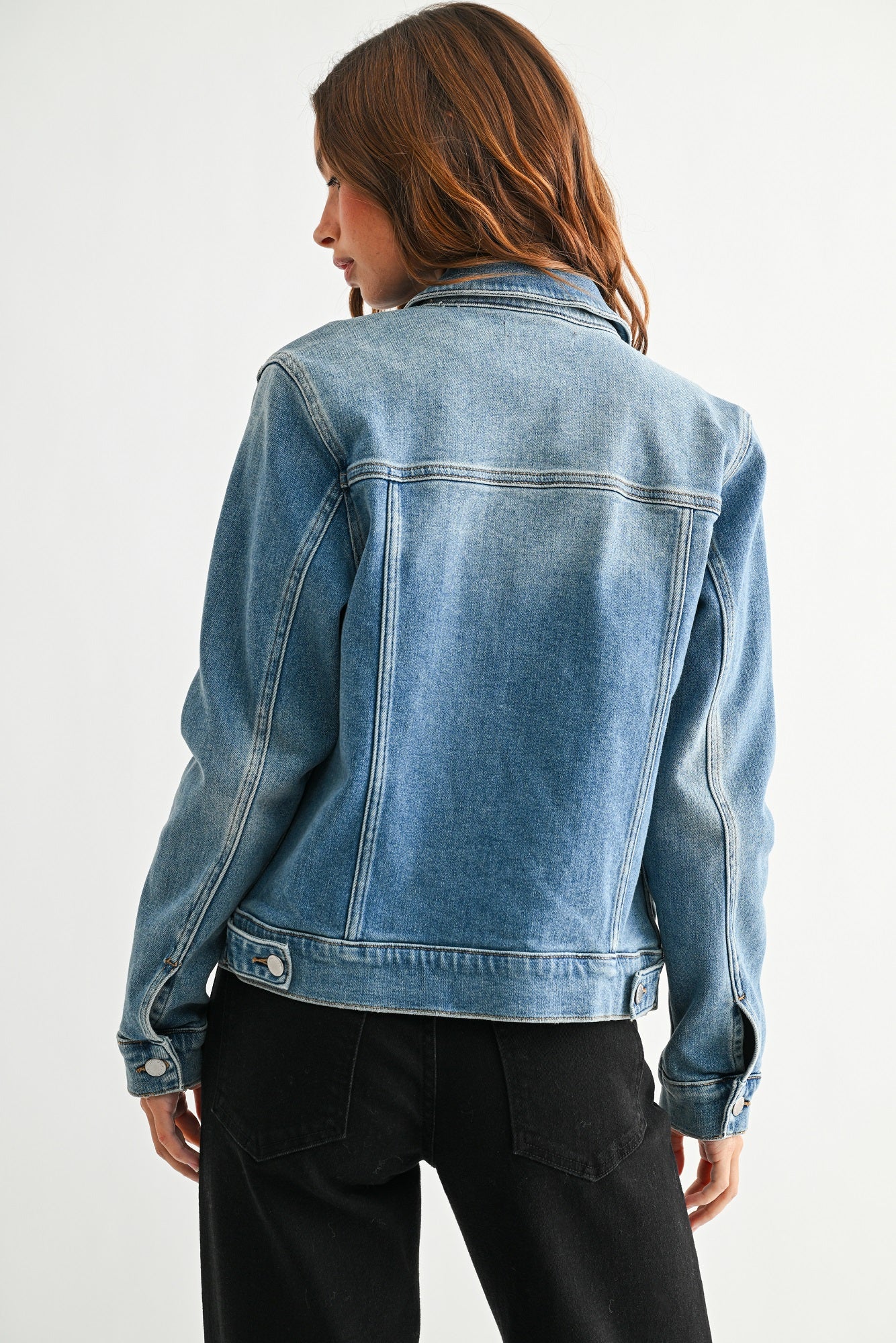 Person wearing a blue denim jacket on a white background