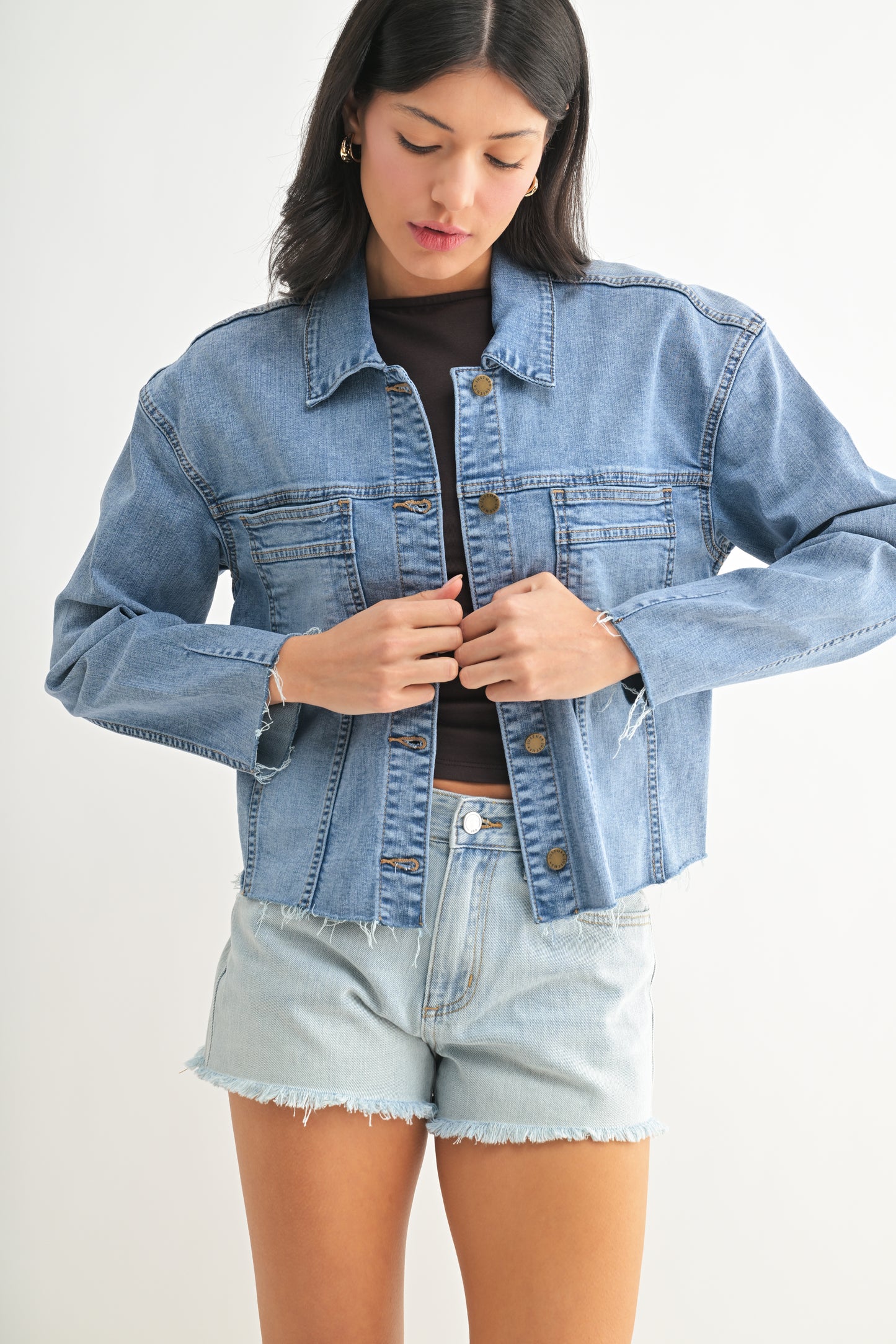 Woman wearing a denim jacket and shorts on a white background