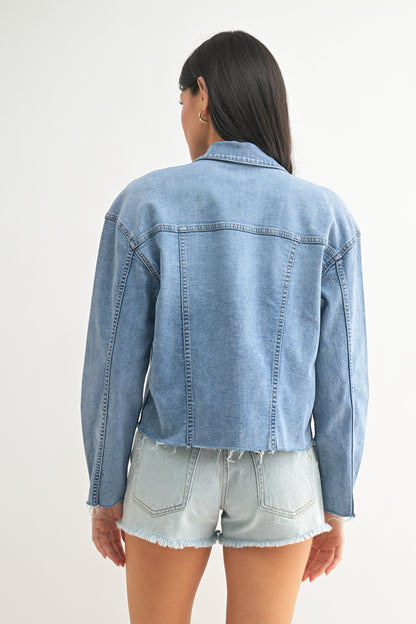 Person wearing a light blue denim jacket and denim shorts on a white background