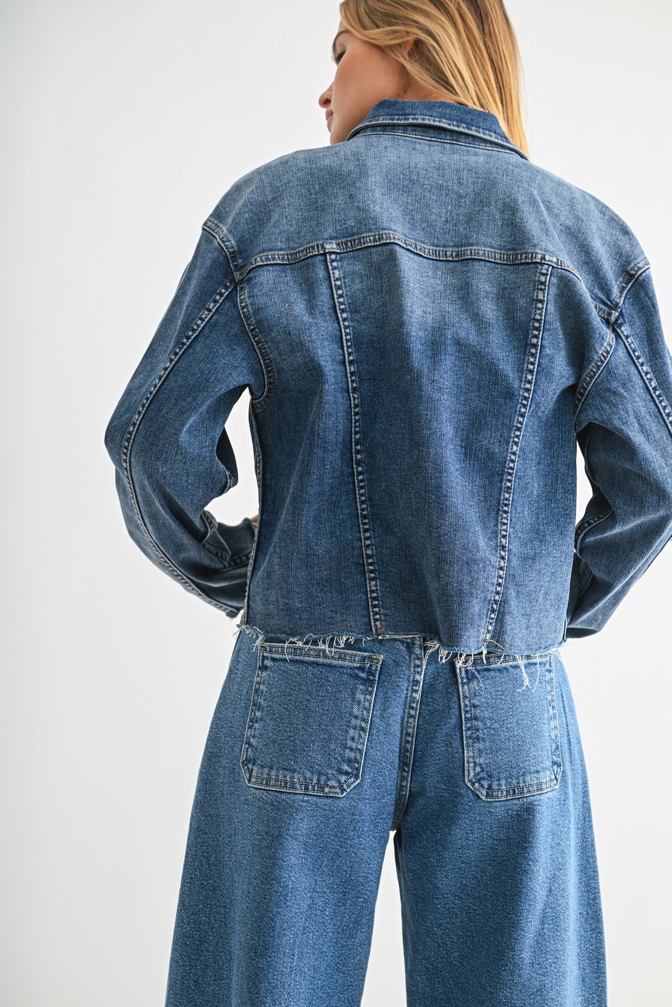 Person wearing a blue denim jacket and jeans on a white background