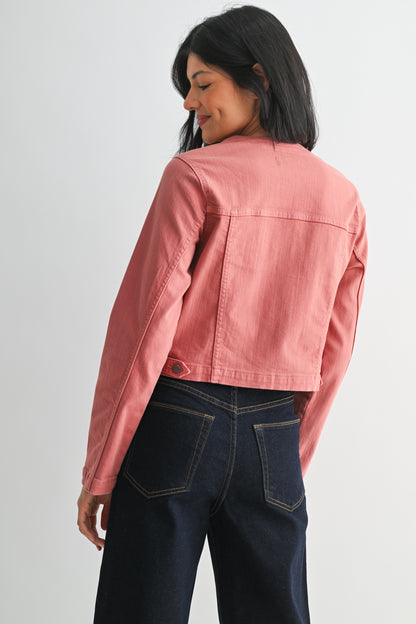 Person wearing a pink denim jacket and dark jeans on a plain background