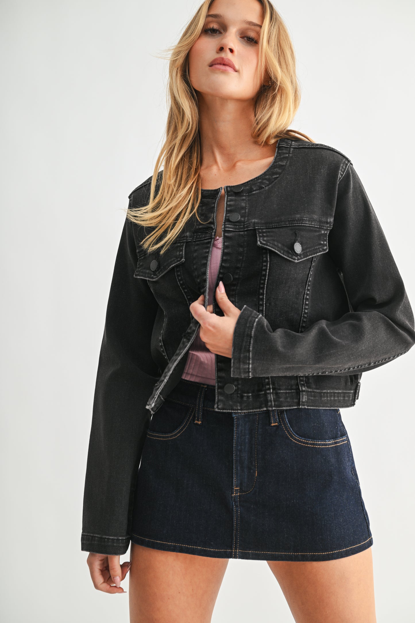 Woman wearing a black denim jacket and skirt on a white background