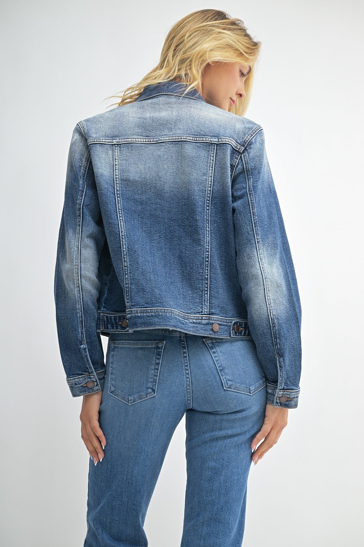 Person wearing a blue denim jacket and jeans on a white background