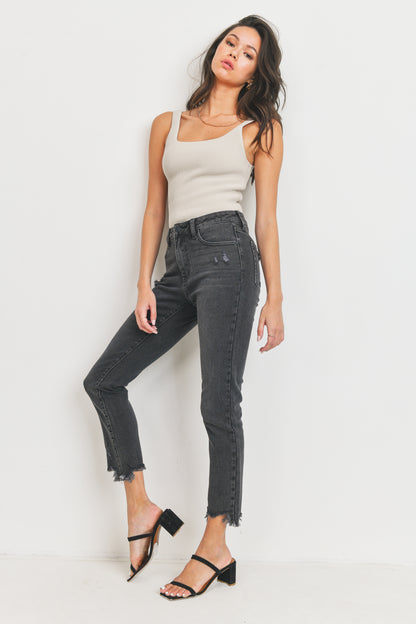 Woman wearing a white tank top and black jeans against a white background