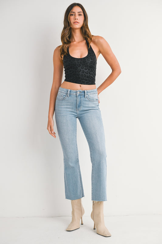 Woman wearing a black tank top and light blue jeans against a white background