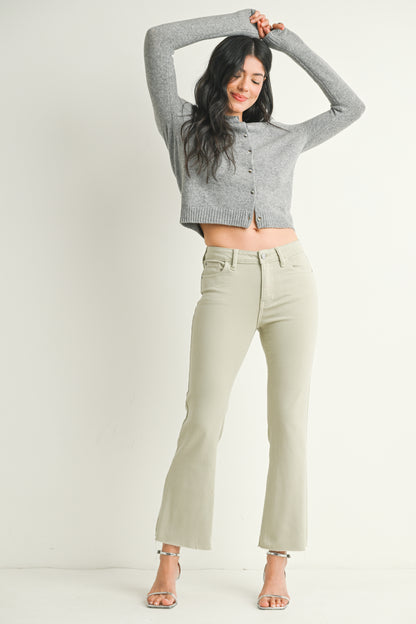 Woman wearing a gray cropped sweater and light green pants on a white background