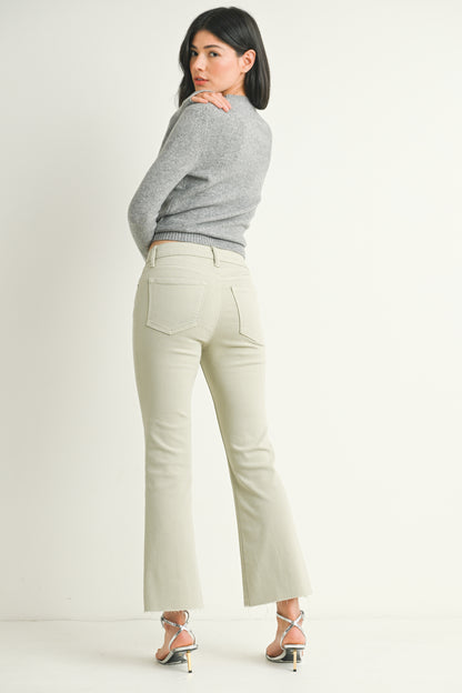 Woman wearing a gray sweater and light green pants on a white background