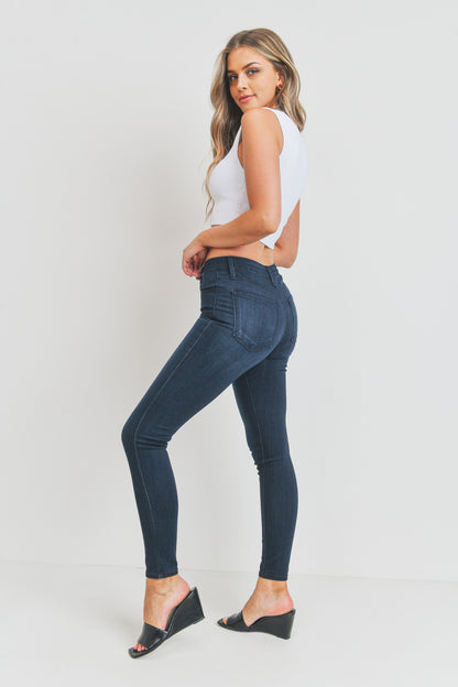 Woman wearing blue jeans and a white top against a plain background