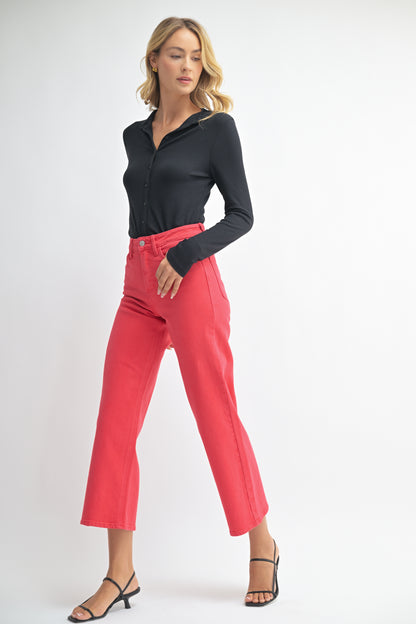 Woman wearing a black top and red pants on a white background
