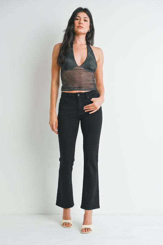 Woman wearing a sheer top and black pants against a white background