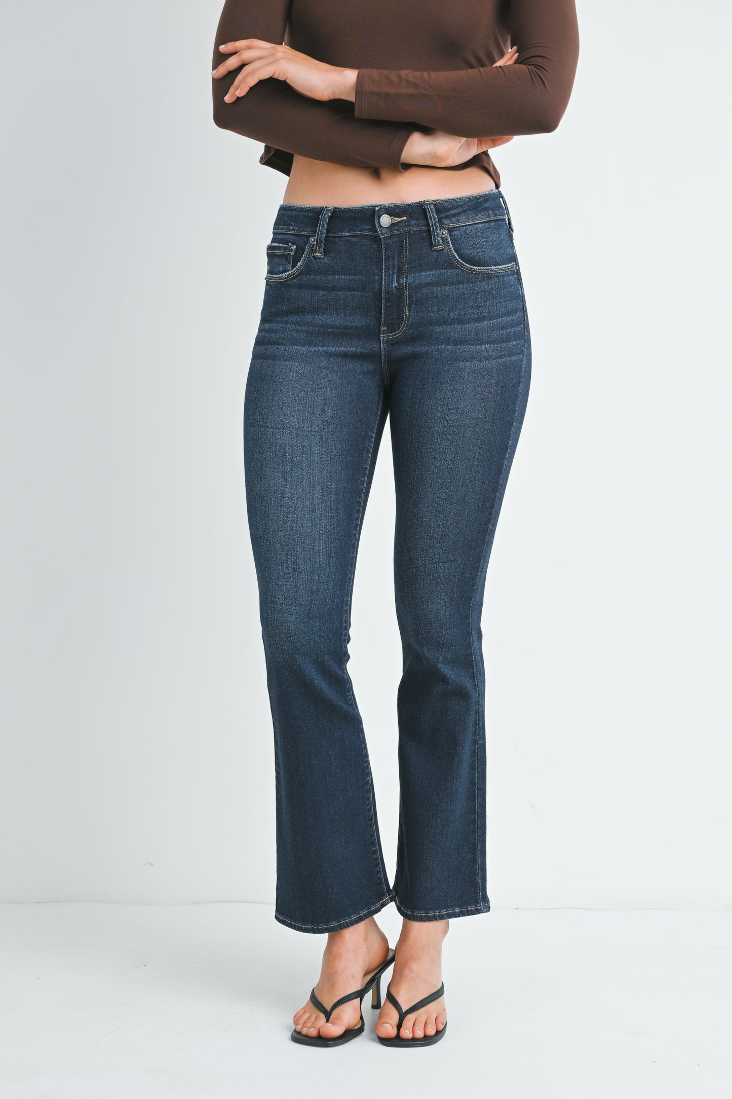 Person wearing blue jeans and a brown top on a white background