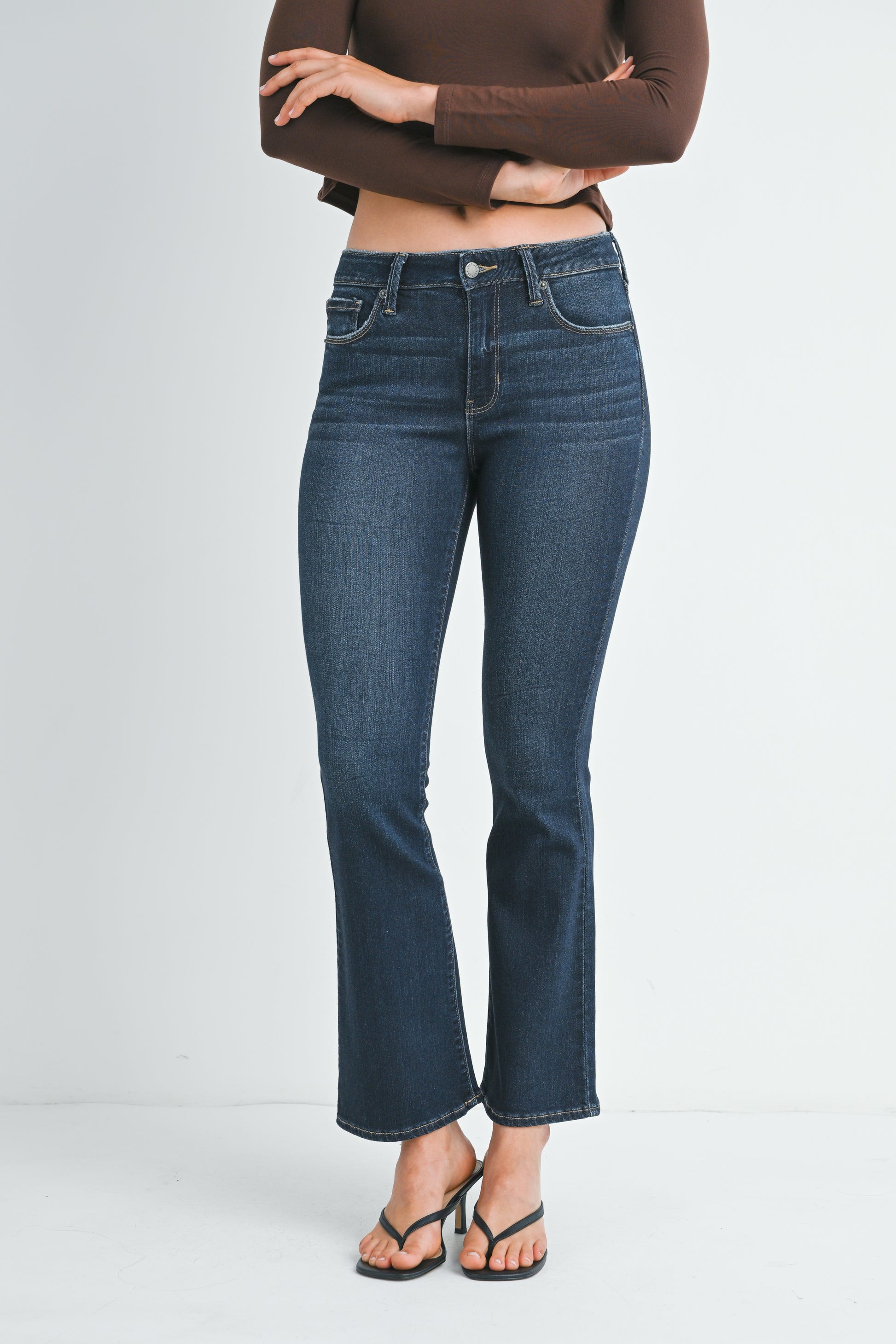 Person wearing blue jeans and a brown top on a white background