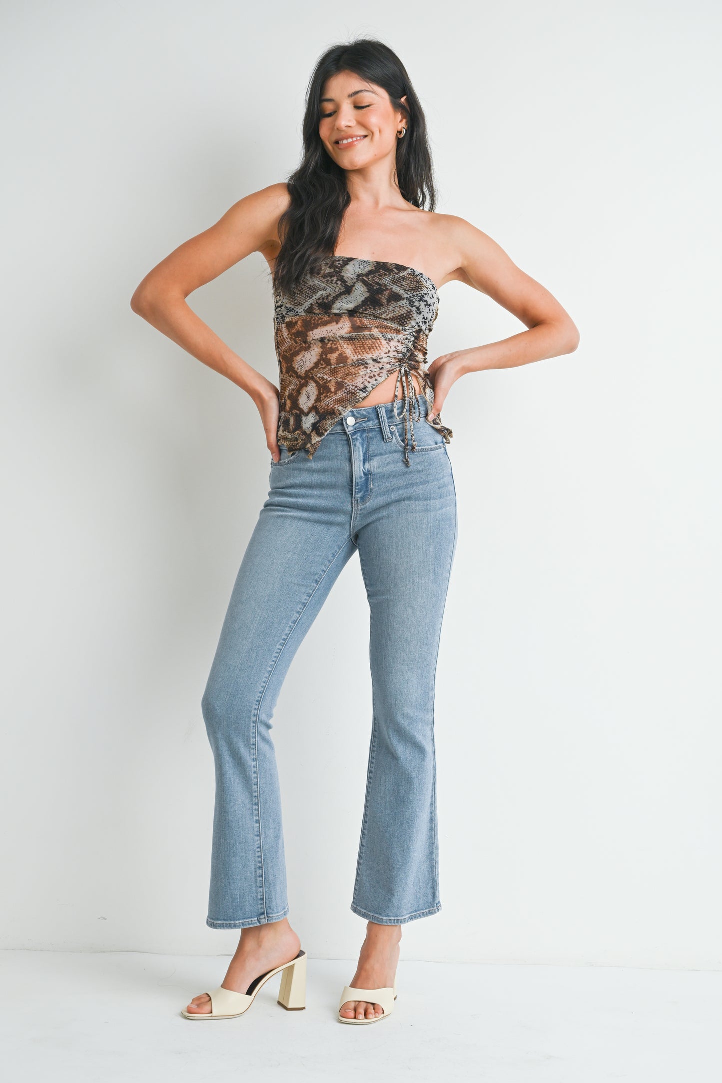 Woman wearing a floral top and blue jeans against a white background