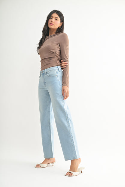 Woman wearing a brown top and light blue jeans on a white background