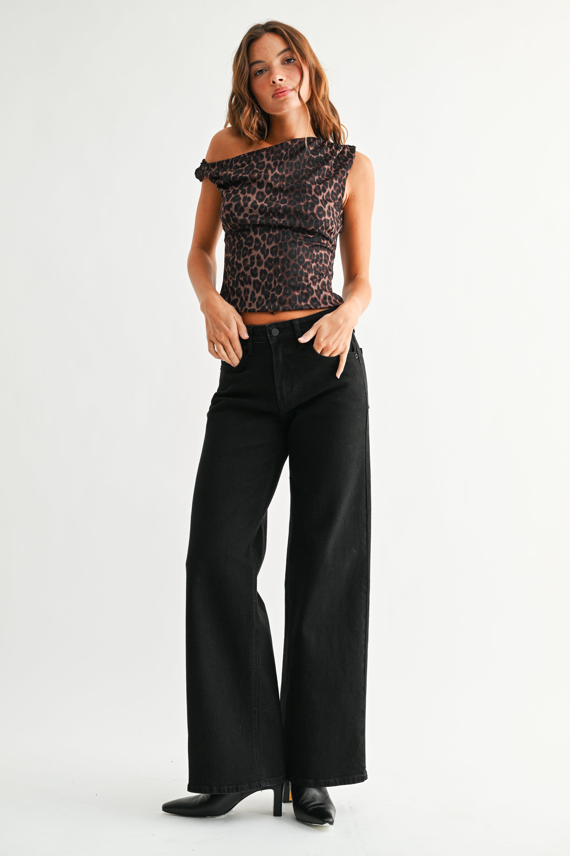 Woman wearing a leopard print top and black wide-leg jeans on a white background
