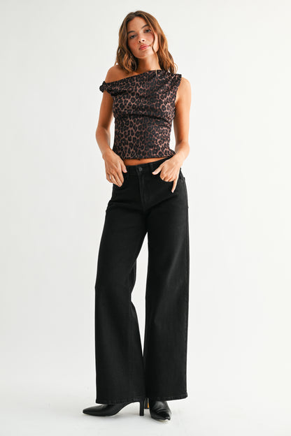 Woman wearing a leopard print top and black wide-leg jeans on a white background
