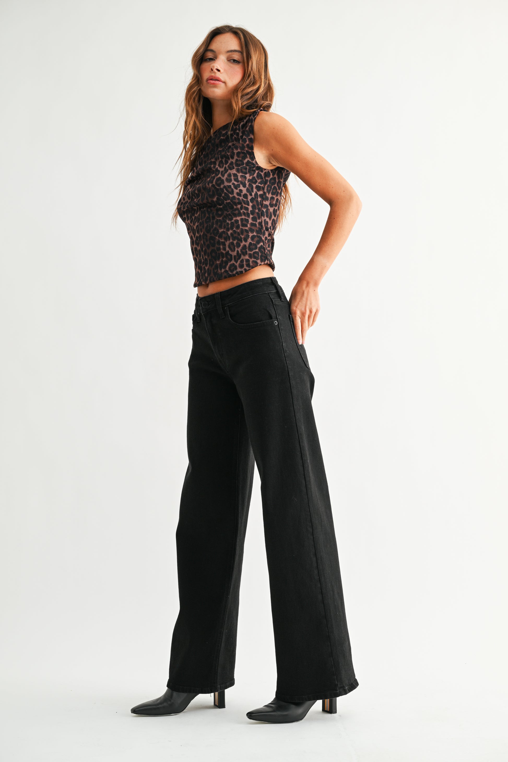 Woman wearing a leopard print top and black wide-leg pants on a white background