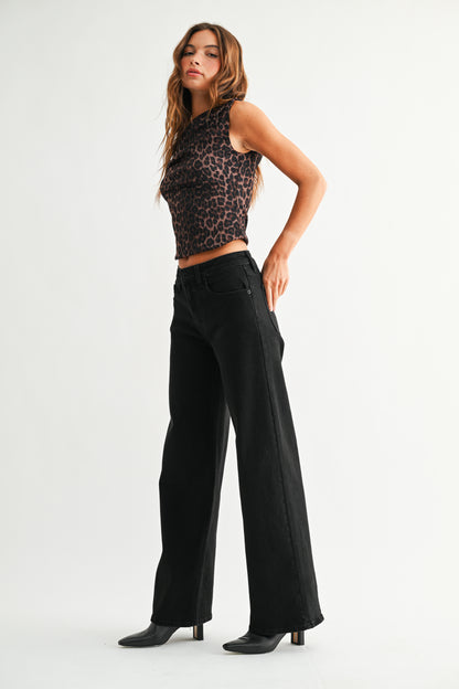 Woman wearing a leopard print top and black wide-leg pants on a white background