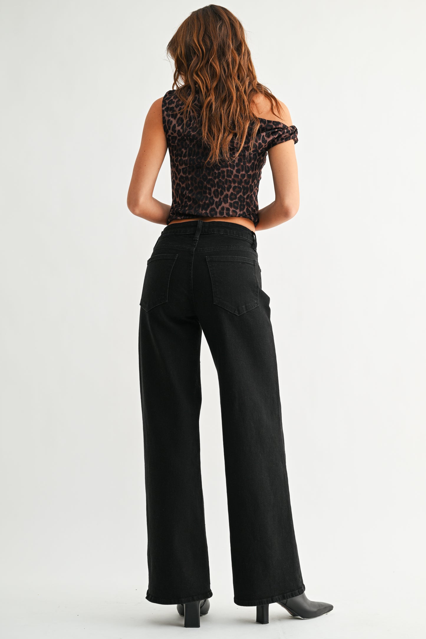 Person wearing a leopard print top and black pants on a white background