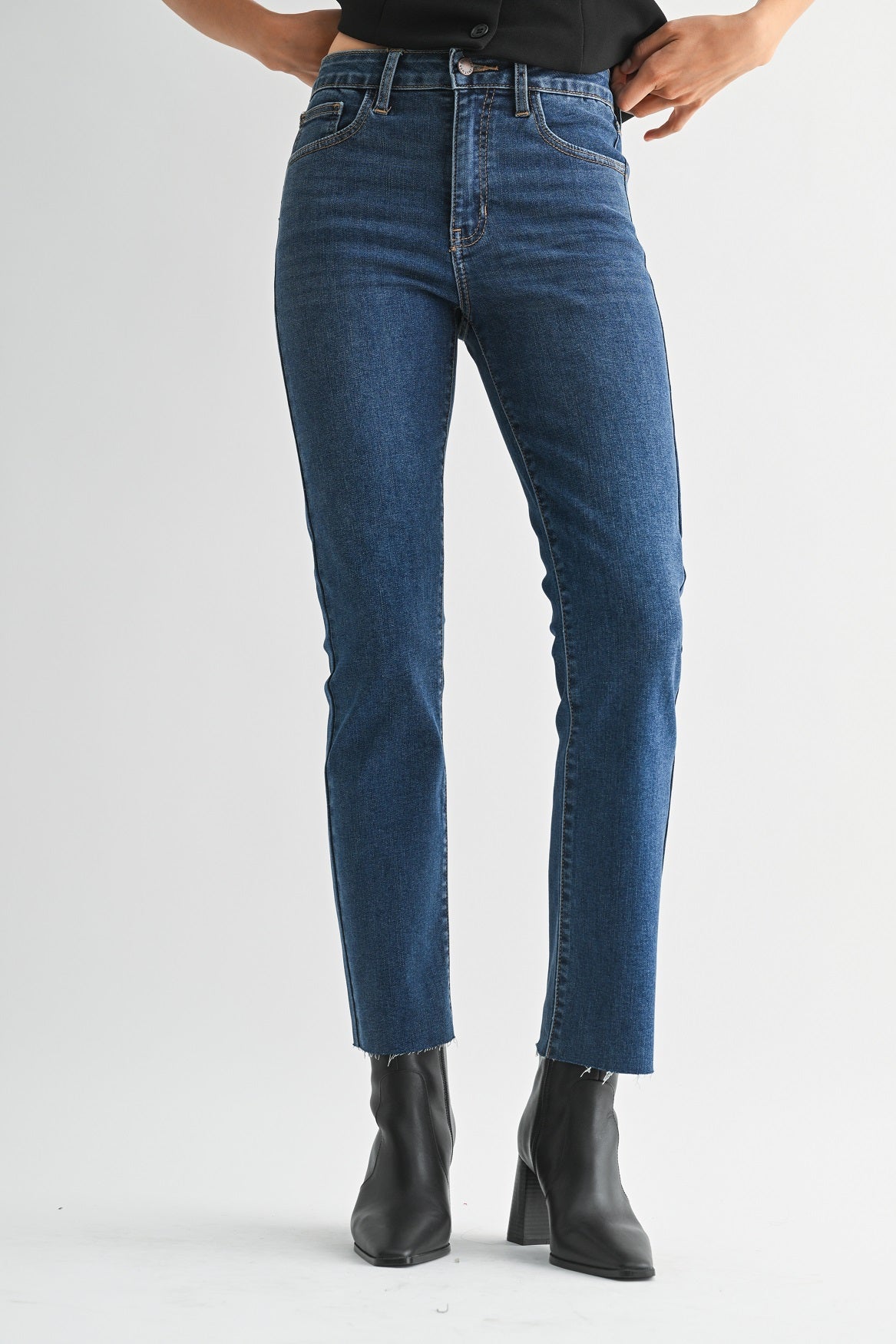 Person wearing blue jeans and black boots on a white background