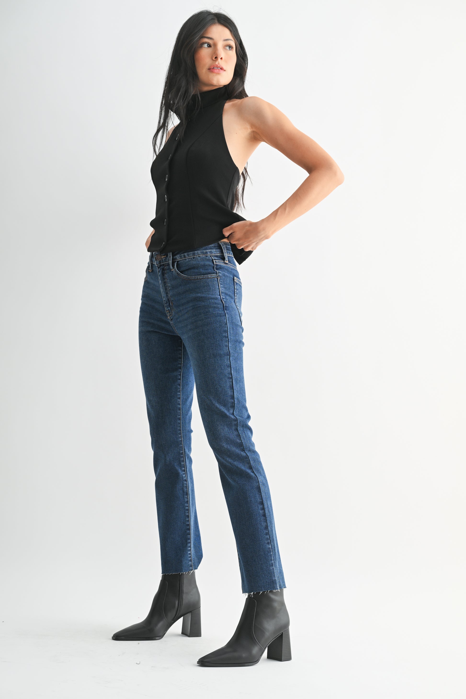 Woman wearing blue jeans and a black top on a white background