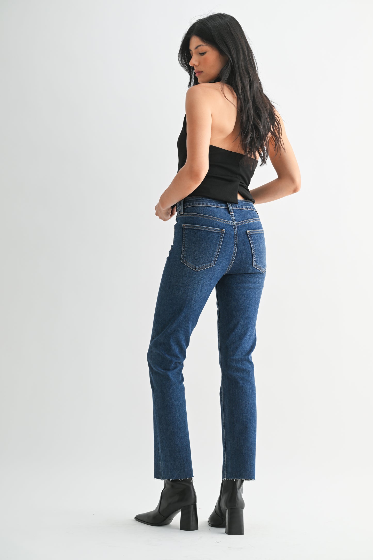 Woman wearing blue jeans and black boots on a white background