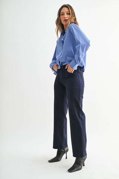 Woman wearing a blue striped shirt and navy pants on a white background