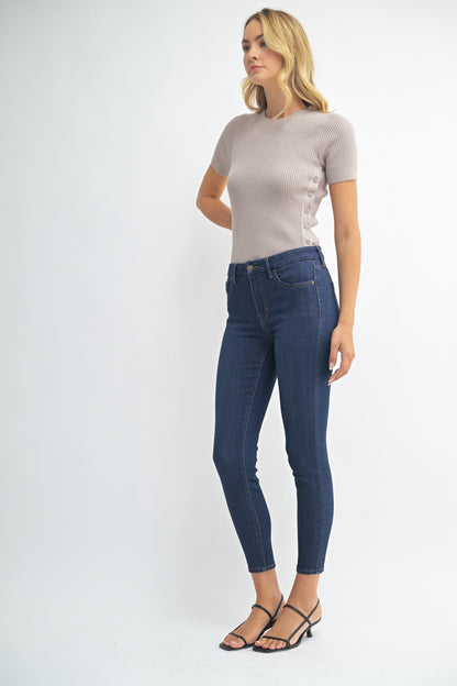 Woman wearing a gray top and blue jeans on a white background