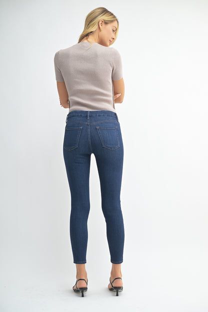 Woman wearing blue jeans and a beige top on a white background