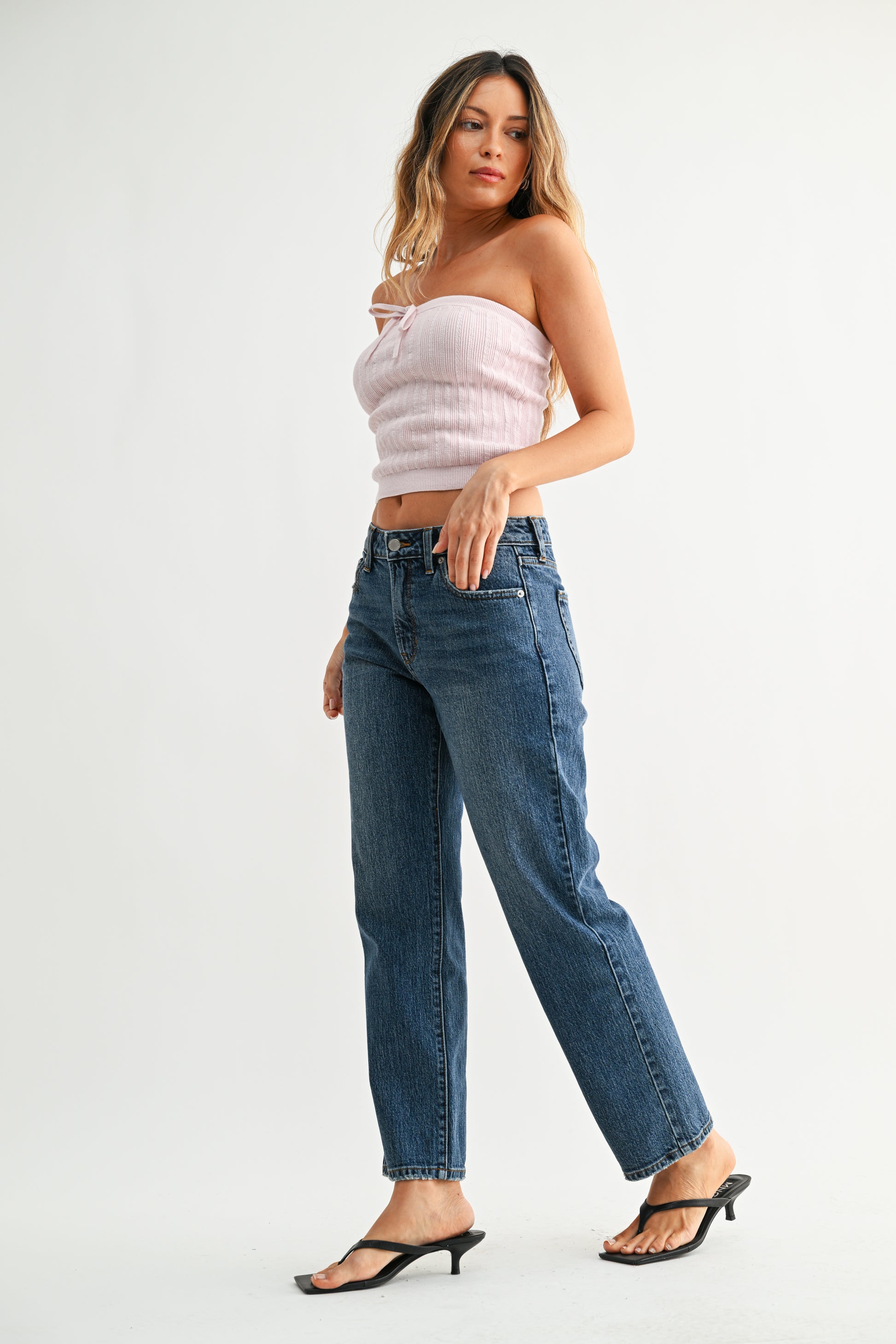 Woman wearing a strapless top and blue jeans on a white background