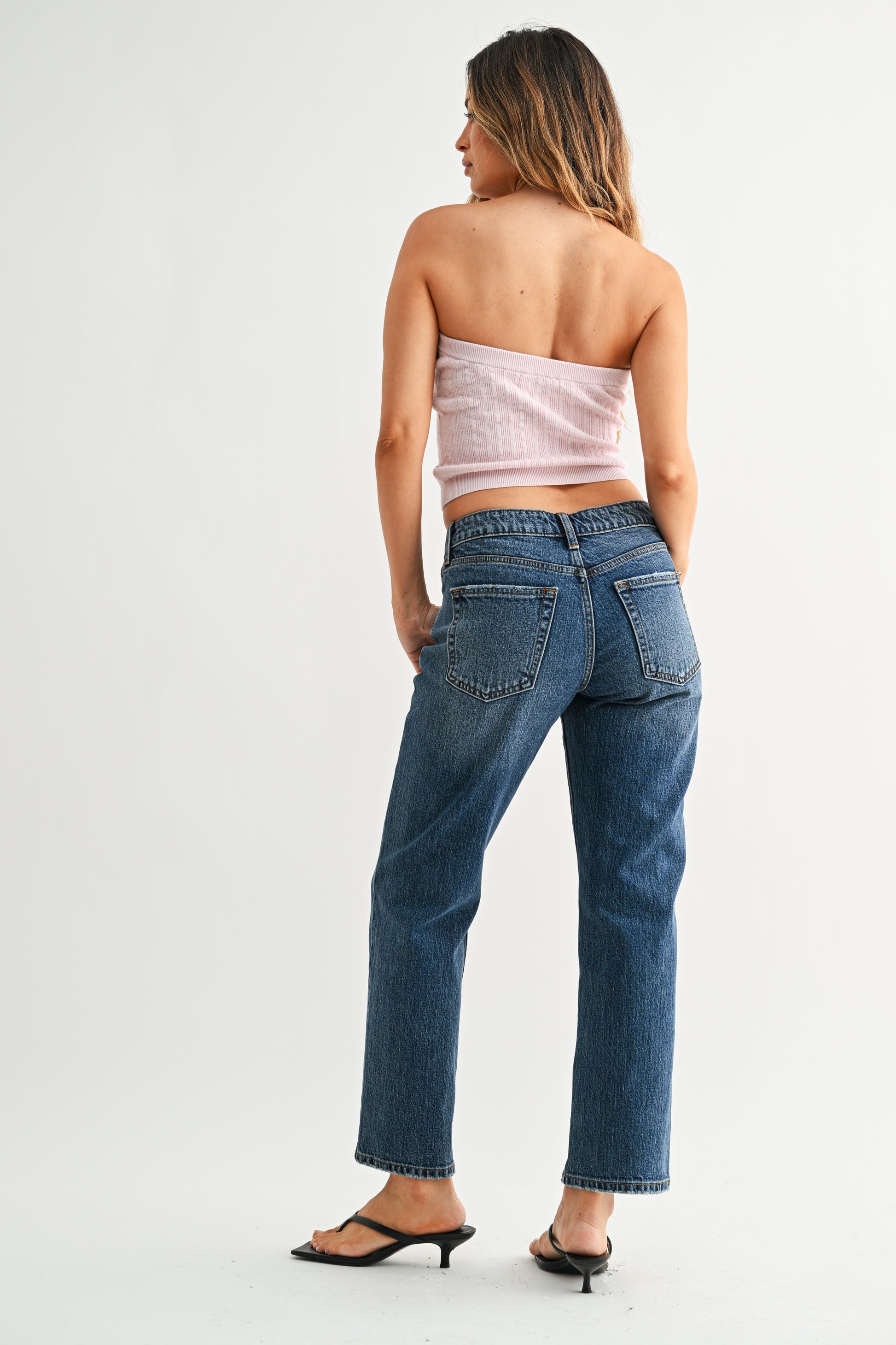 Woman wearing blue jeans and a strapless top on a white background