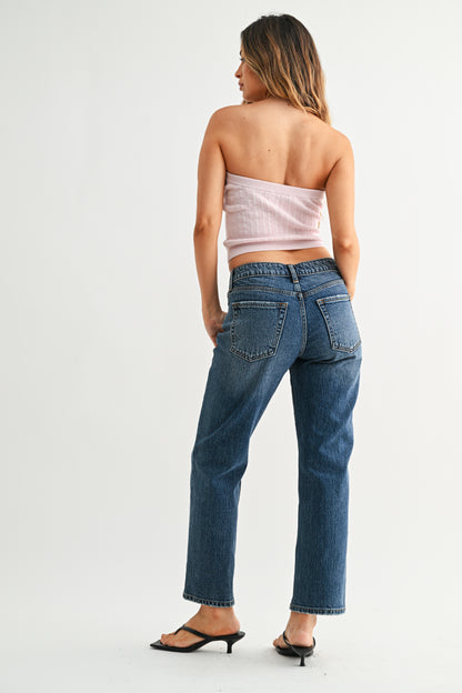 Woman wearing blue jeans and a strapless top on a white background
