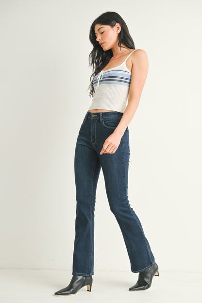 Woman wearing a striped tank top and dark blue jeans on a white background