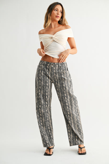 Woman wearing a white off-shoulder top and patterned pants on a white background