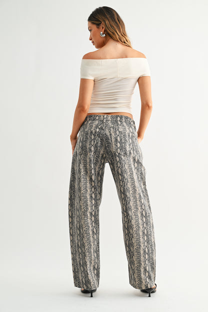 Woman wearing a white off-shoulder top and patterned pants on a white background