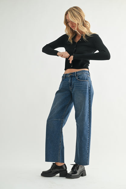 Woman wearing a black top and blue jeans on a white background