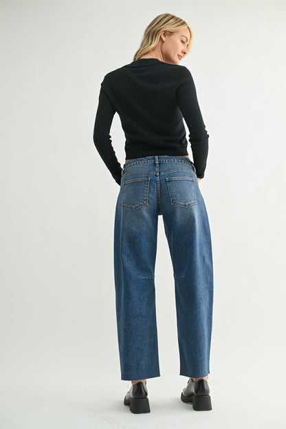 Woman wearing blue jeans and a black top on a white background