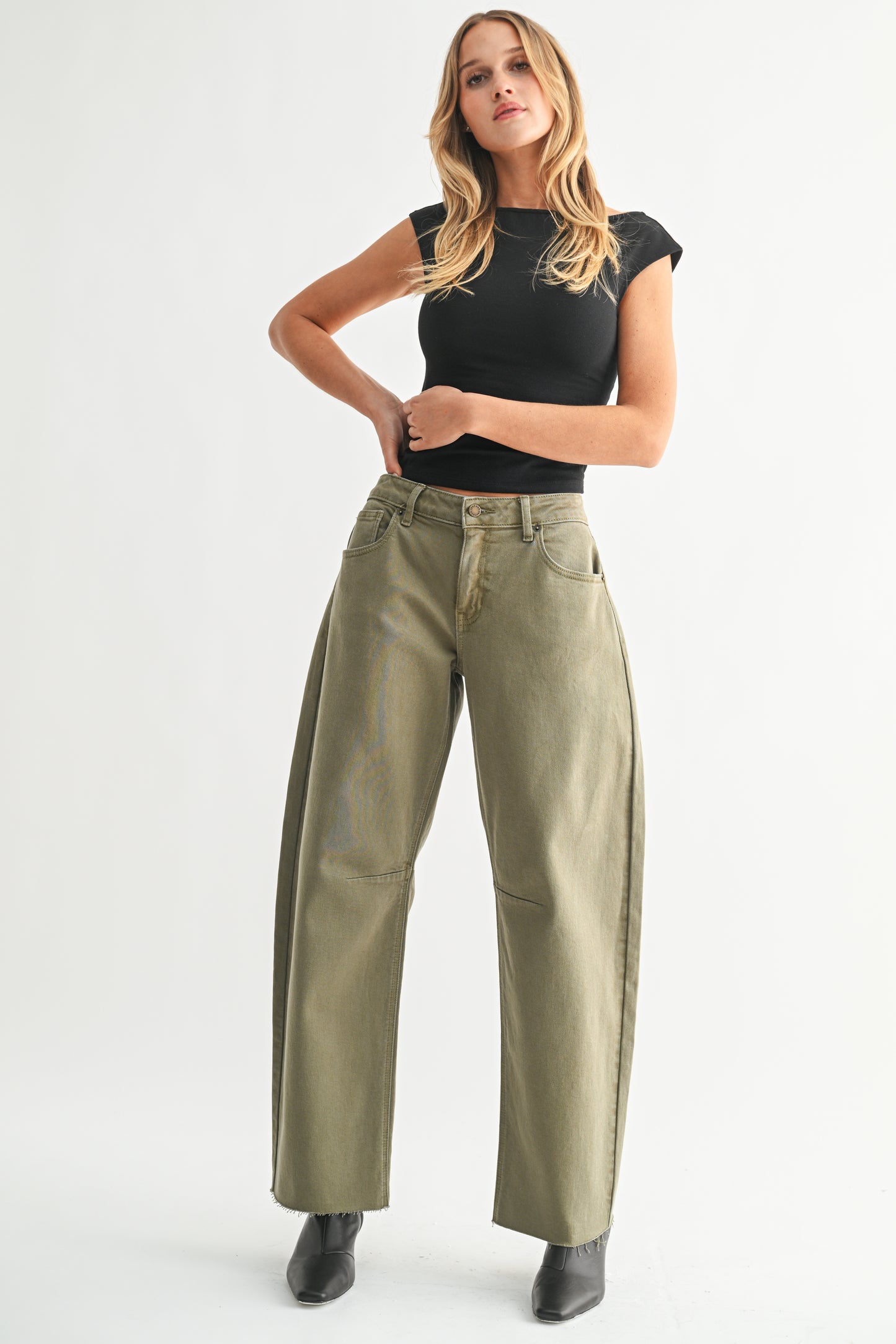 Woman wearing a black top and green pants on a white background