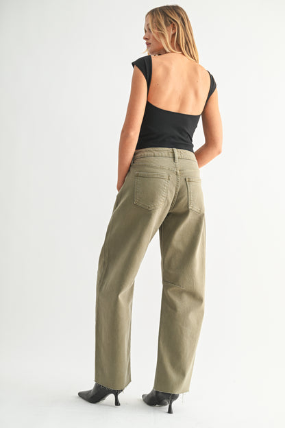 Woman wearing beige pants and a black top on a white background